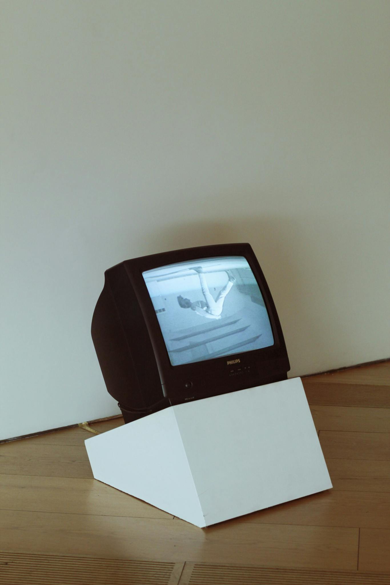 A classic vintage CRT television set on a minimalist modern stand in a sparsely decorated room.