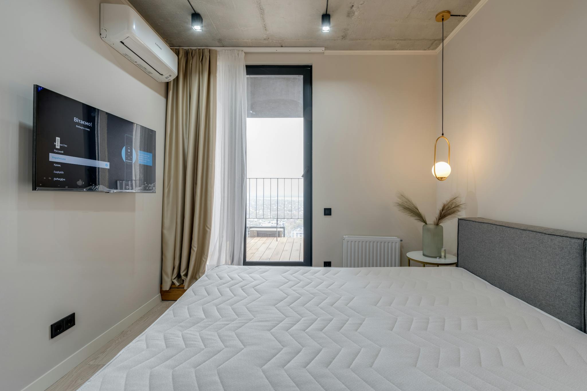 Minimalistic bedroom featuring a balcony, flat screen TV, and elegant lighting.